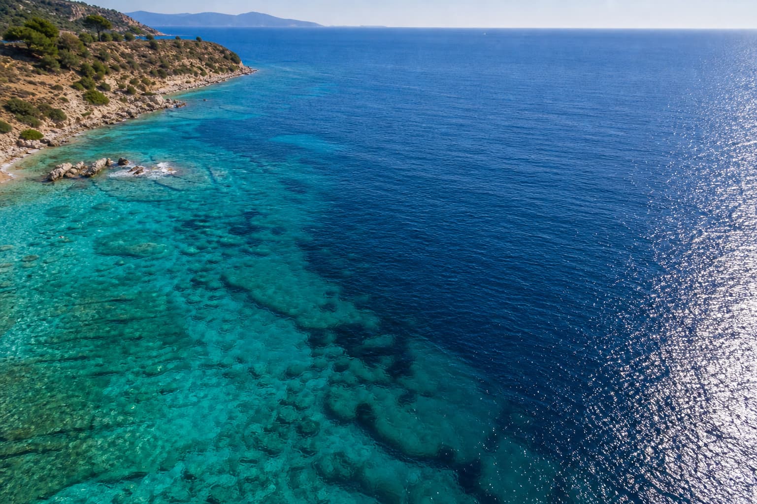 Vue aérienne par drone de la côte méditerranéenne montrant des eaux turquoise peu profondes passant progressivement au bleu profond de l
